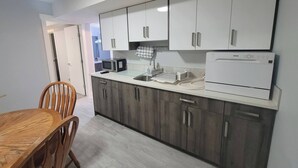 A modern kitchen with white cabinets, a microwave, a coffee maker, and a dishwasher. - Luxurious Home Away From Home With Aircon (Airdrie)