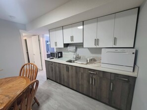 A modern kitchen with white cabinets, a microwave, a coffee maker, and a dishwasher. - Luxurious Home Away From Home With Aircon (Airdrie)