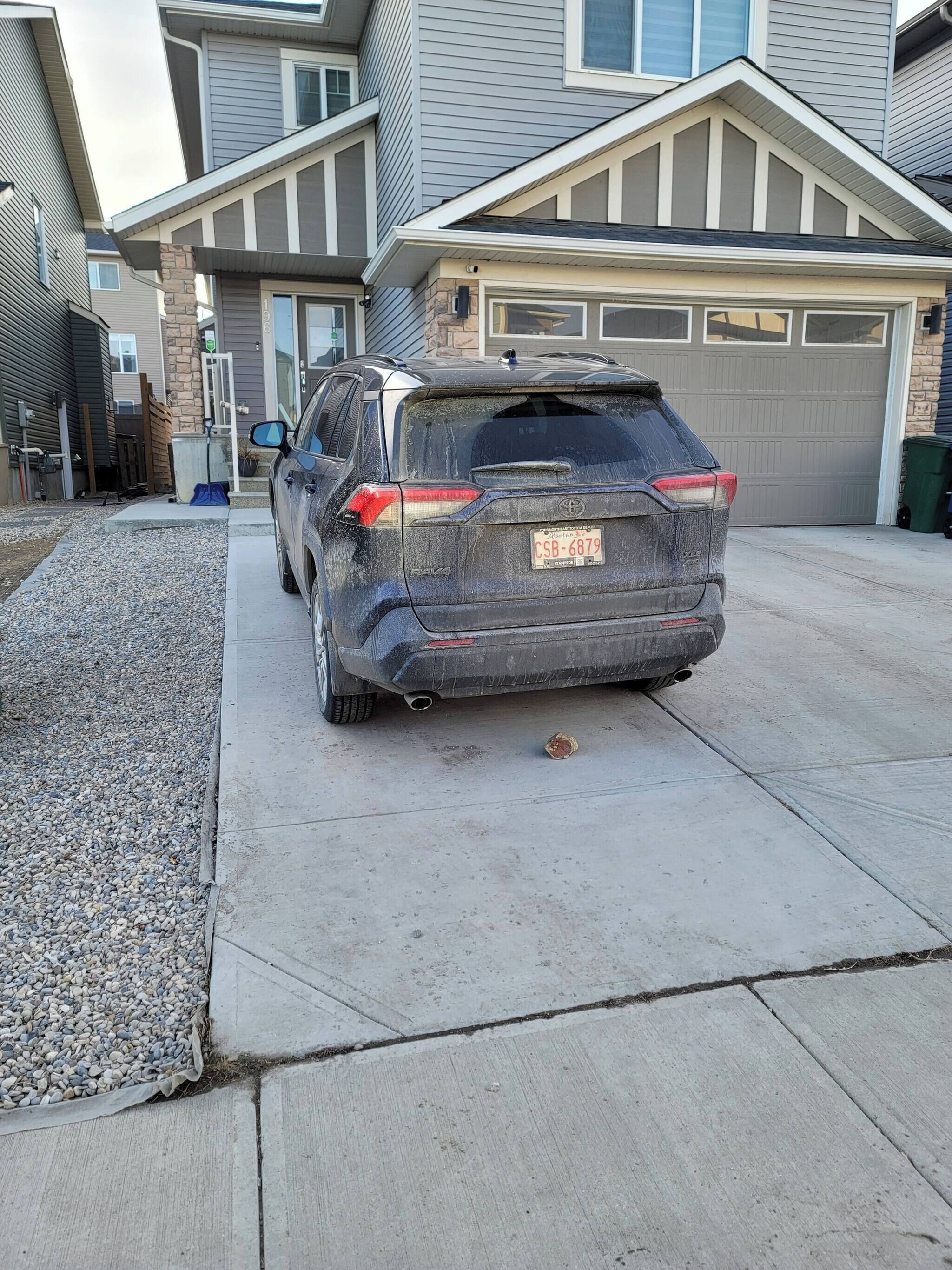 Una entrada de casa con un SUV estacionado.