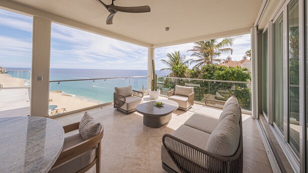 Ein geräumiger Balkon mit Meerblick, ausgestattet mit einer Couch, Stühlen und einem Couchtisch.