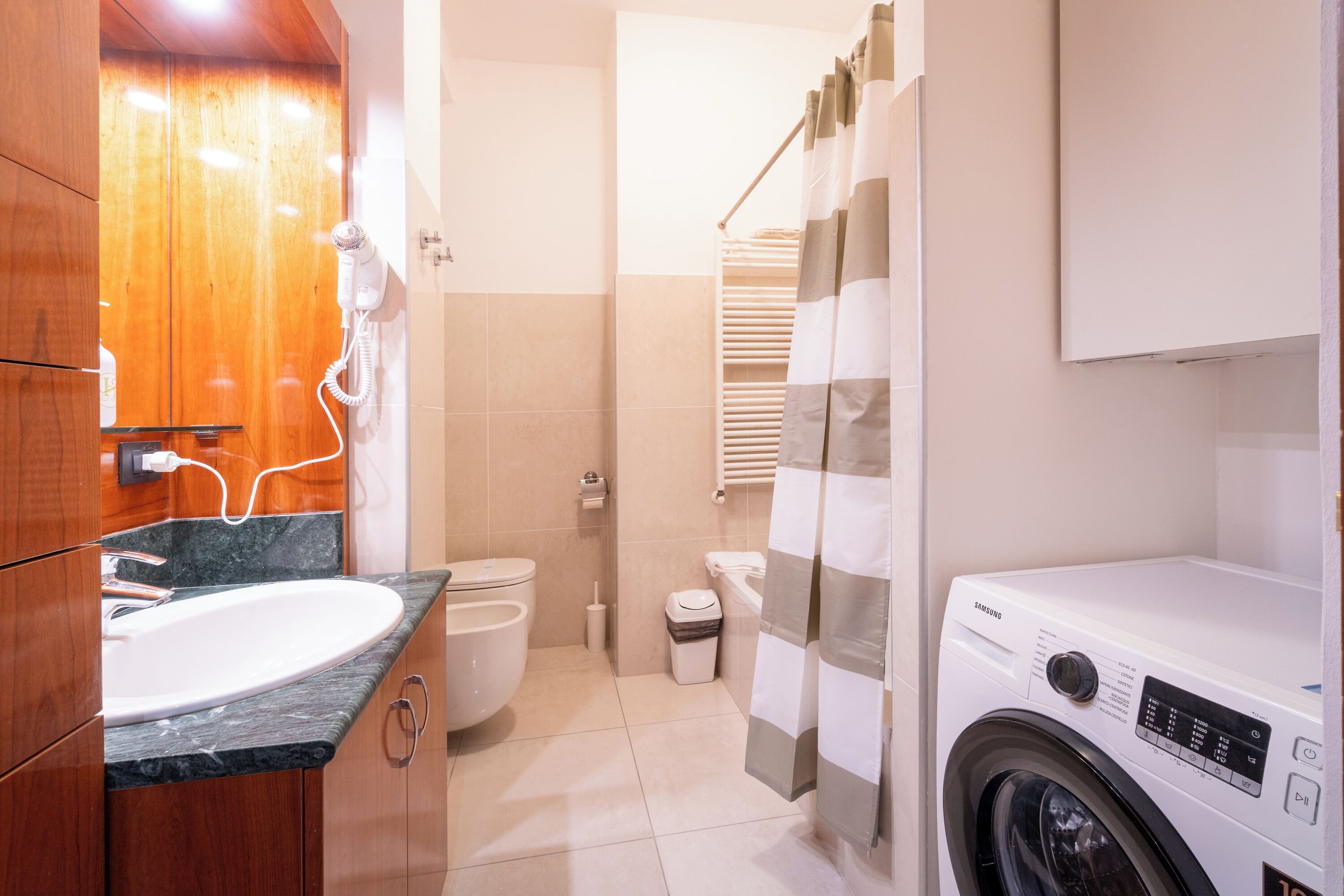 Une petite salle de bain comprenant un lavabo, des toilettes et un lave-linge.