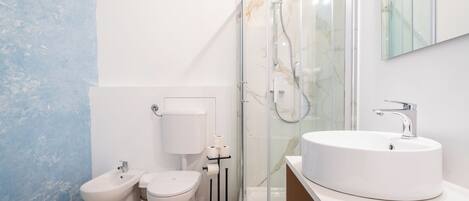A modern bathroom with a toilet, bidet, and a glass-enclosed shower.