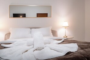 A neatly made bed with white linens and a brown blanket, a bedside lamp, and a mirror on the wall. - Vitti's home Verona 6 (Verona)