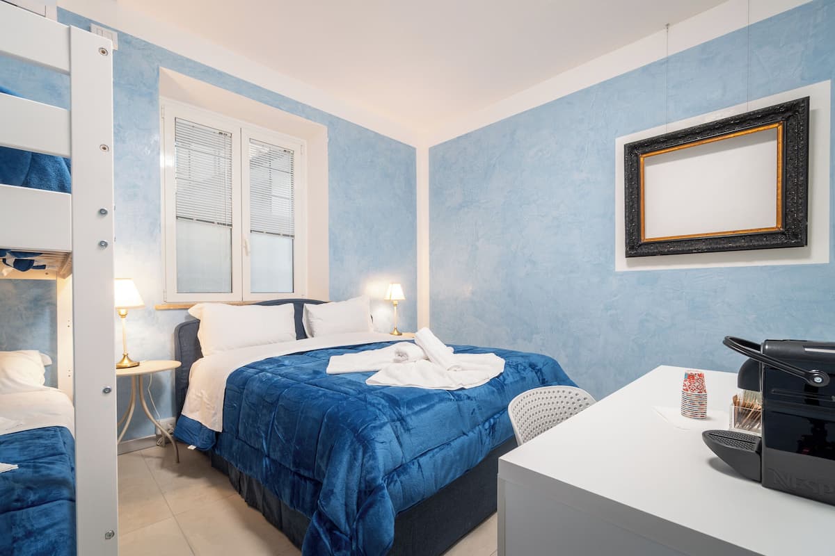 Una habitación de hotel con cama, mesita de noche, lámpara y cafetera.