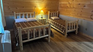 Une cabane avec deux lits en bois, une petite table avec une lampe et un radiateur.