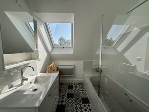 Une salle de bain moderne avec une lucarne, une baignoire et une douche.