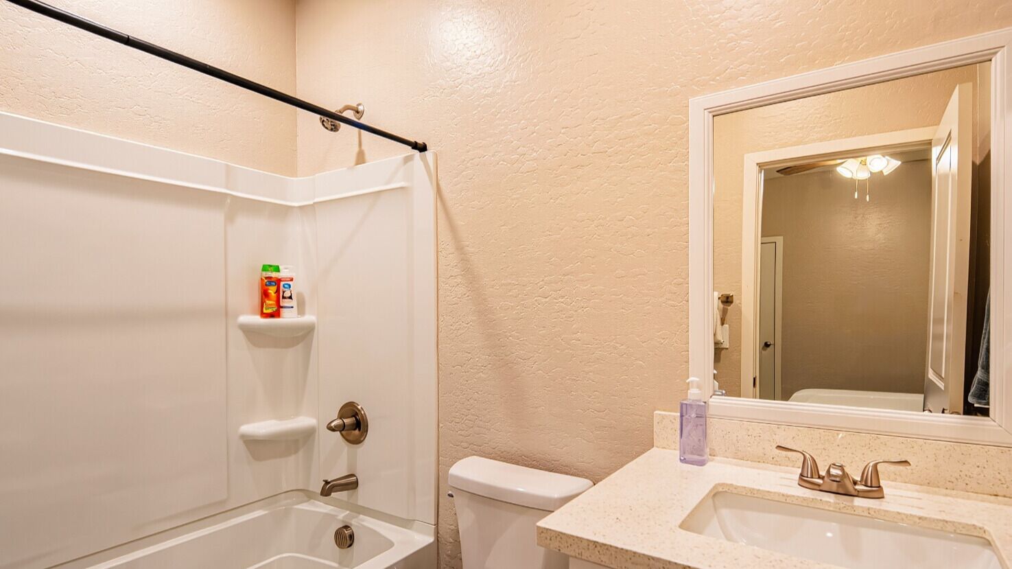 Un baño con ducha, inodoro, lavabo y espejo.