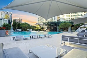 A rooftop pool area with lounge chairs, umbrellas, and a view of high-rise buildings. - Level 18 City View Private Apartment (Surfers Paradise)
