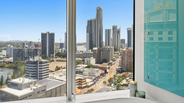 Blick auf eine Stadtlandschaft von einem Hochhaus mit moderner Architektur und blauem Himmel.