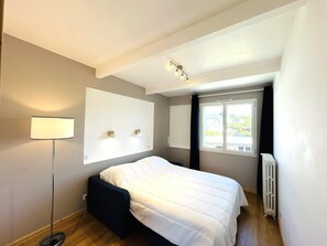 Una camera da letto con un letto, una lampada da terra, un termosifone e una finestra.