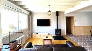 Uma sala de estar moderna com um sofá, uma televisão, uma lareira e uma janela grande.
