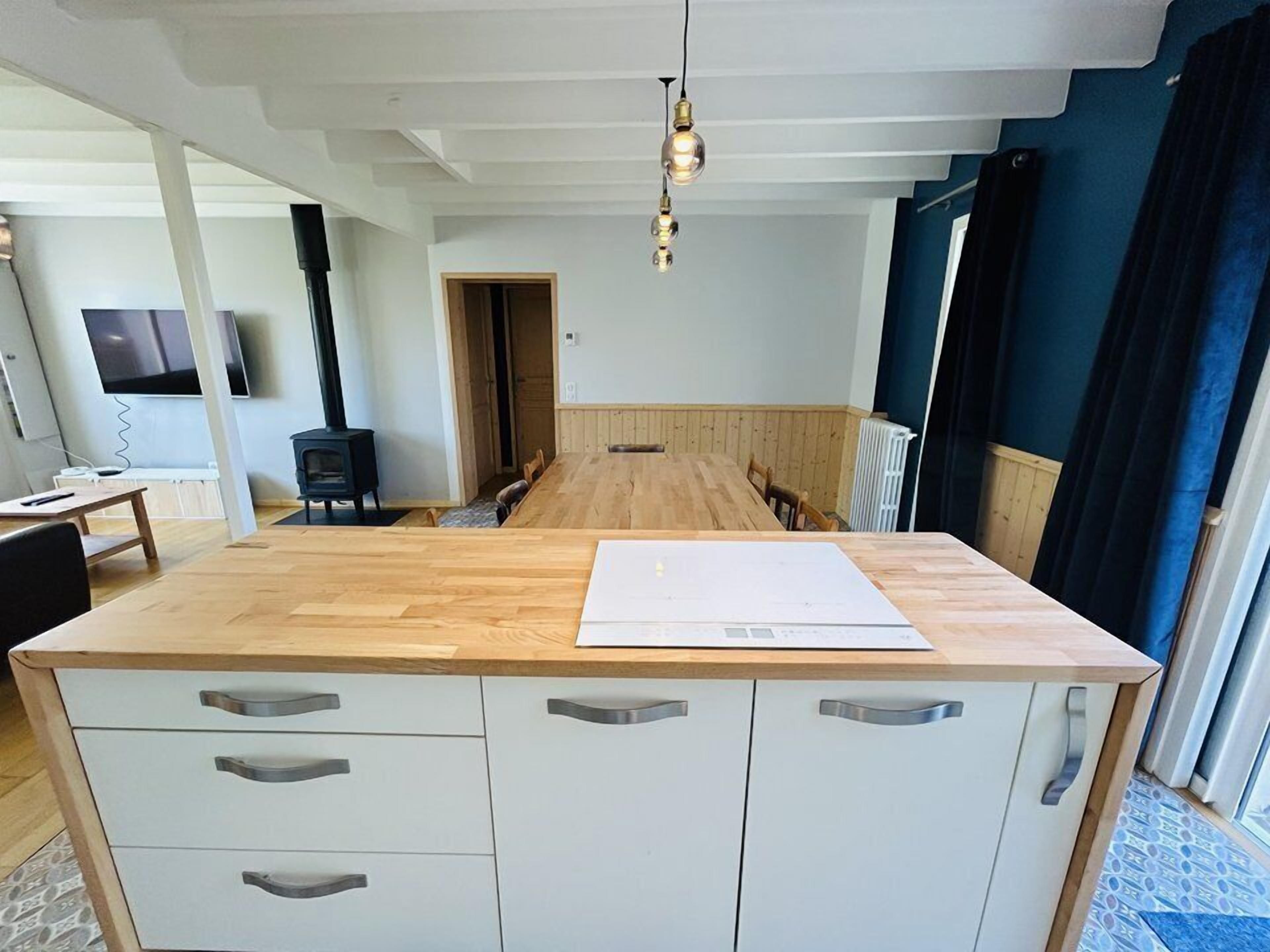 A modern kitchen with a wooden island, white cabinets, and a built-in stove.