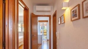 A hallway with wooden doors, an air conditioning unit, and framed pictures on the wall. - Casa do Limoeiro 4-bdr house in a quiet square, 10 min walk from Cascais center. (Cascais)