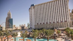 A large hotel with a pool area, palm trees, and a casino in the background.