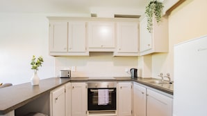 A kitchen with white cabinets, a built-in oven, a sink, and a countertop. - Family & Group-Friendly Galway Apartment (Galway)