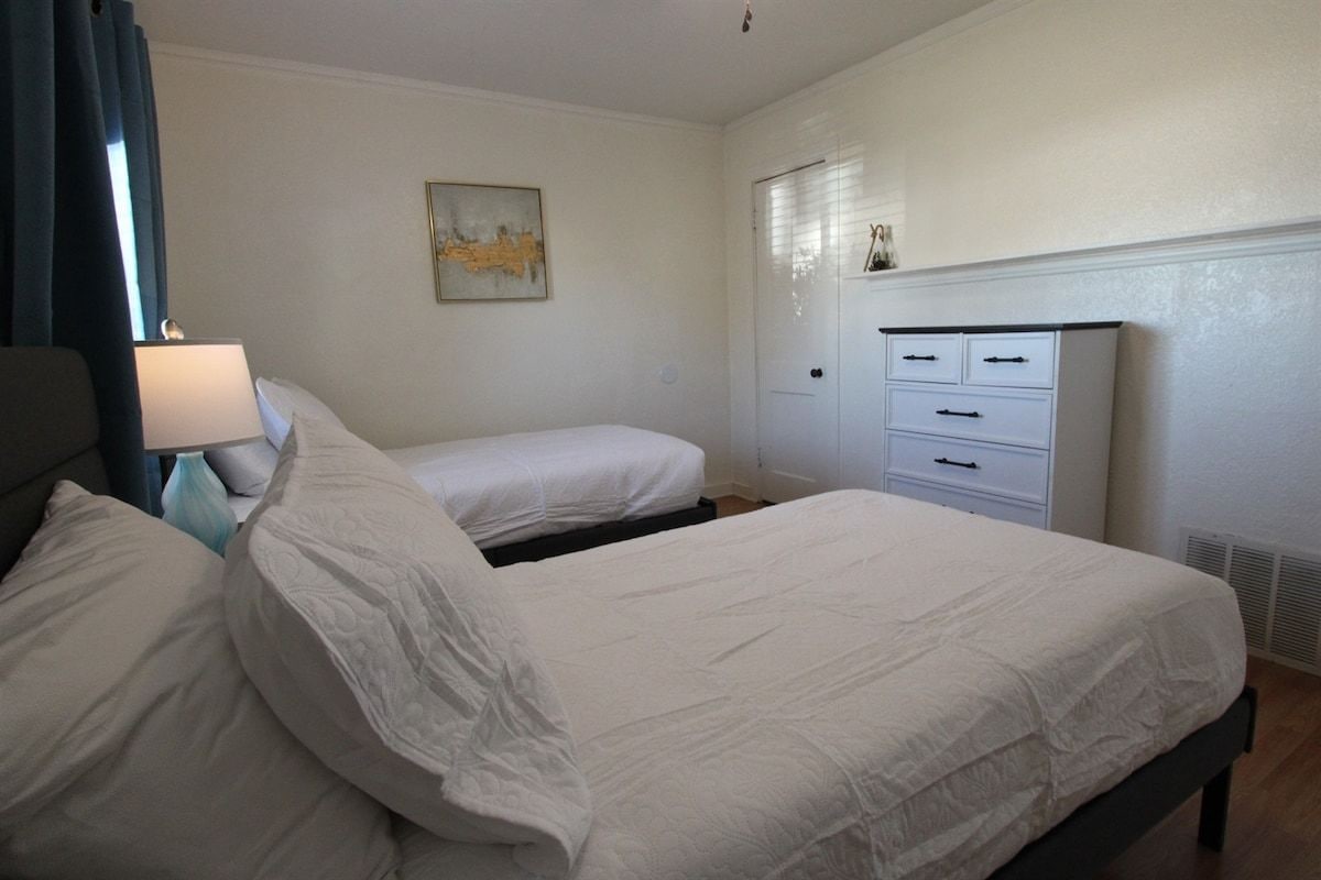 Ein Hotelzimmer mit einem Bett, zwei Nachttischen, einer Kommode und einem Bild an der Wand.