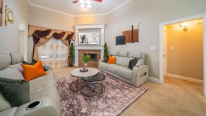A living room with a fireplace, two sofas, a coffee table, and a ceiling fan. - Hill Country | Spacious 4BR Retreat (Abilene)