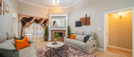 Un salon avec une cheminée, deux canapés, une table basse et un ventilateur de plafond.