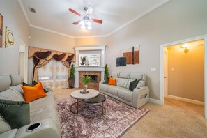 A living room with a fireplace, two sofas, a coffee table, and a ceiling fan.