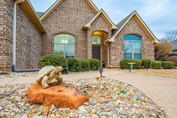 A brick house with a stone sculpture in the front yard.