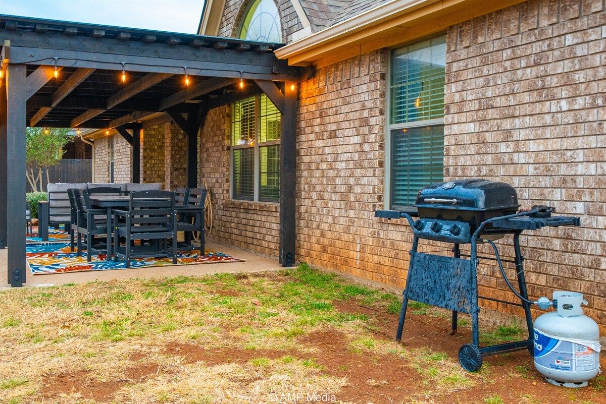 Une terrasse extérieure équipée d’un barbecue, de sièges et d’une bouteille de gaz.