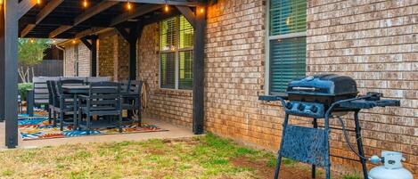 Pérgola exterior con parrilla, asientos y tanque de gas.
