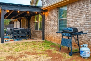 An outdoor patio with a grill, seating, and a gas tank.
