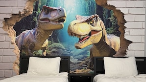 A bedroom with two beds, white bedding, and a mural of dinosaurs on the wall. - Raptor Ridge - Your Abilene Adventure Basecamp (Abilene)
