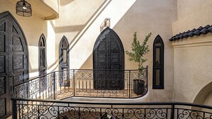 A courtyard with a wrought iron balcony railing, a potted plant, and a large black door. - Authentic Marrakech Riad in the Heart of the Medina (Marrakesh)