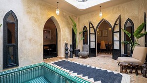 A spacious interior with high ceilings, arched doorways, and a central seating area with a patterned rug. - Authentic Marrakech Riad in the Heart of the Medina (Marrakesh)