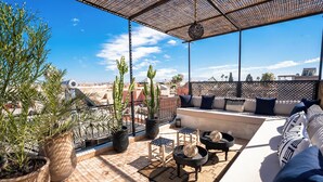A rooftop terrace with a seating area, potted plants, and a view of the cityscape. - Authentic Marrakech Riad in the Heart of the Medina (Marrakesh)