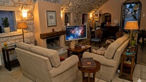 Un salón acogedor con paredes de piedra, una chimenea, un televisor y asientos cómodos.