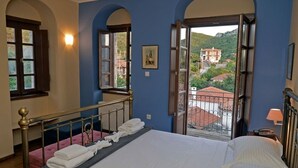 Un dormitorio con cama, ventana y vista a un edificio.