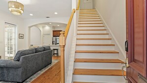 A staircase with wooden steps and a wooden handrail, leading to a landing with a door. - Savannah Home, Sleeps 6, Prime Location (Savannah)