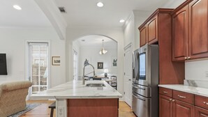 A modern kitchen with a central island, stainless steel appliances, and wooden cabinets. - Savannah Home, Sleeps 6, Prime Location (Savannah)