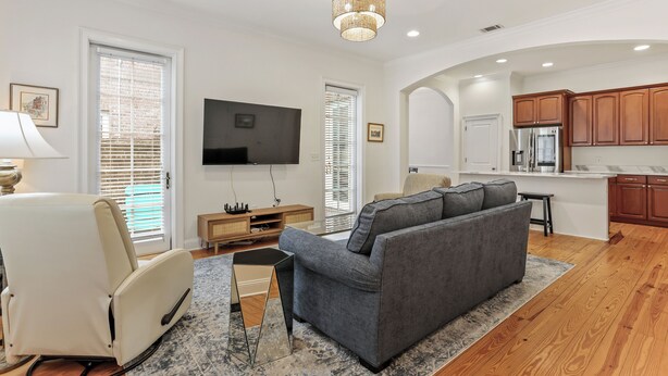A modern living room with a gray sofa, a beige armchair, and a flat-screen TV. - Savannah Home, Sleeps 6, Prime Location (Savannah)
