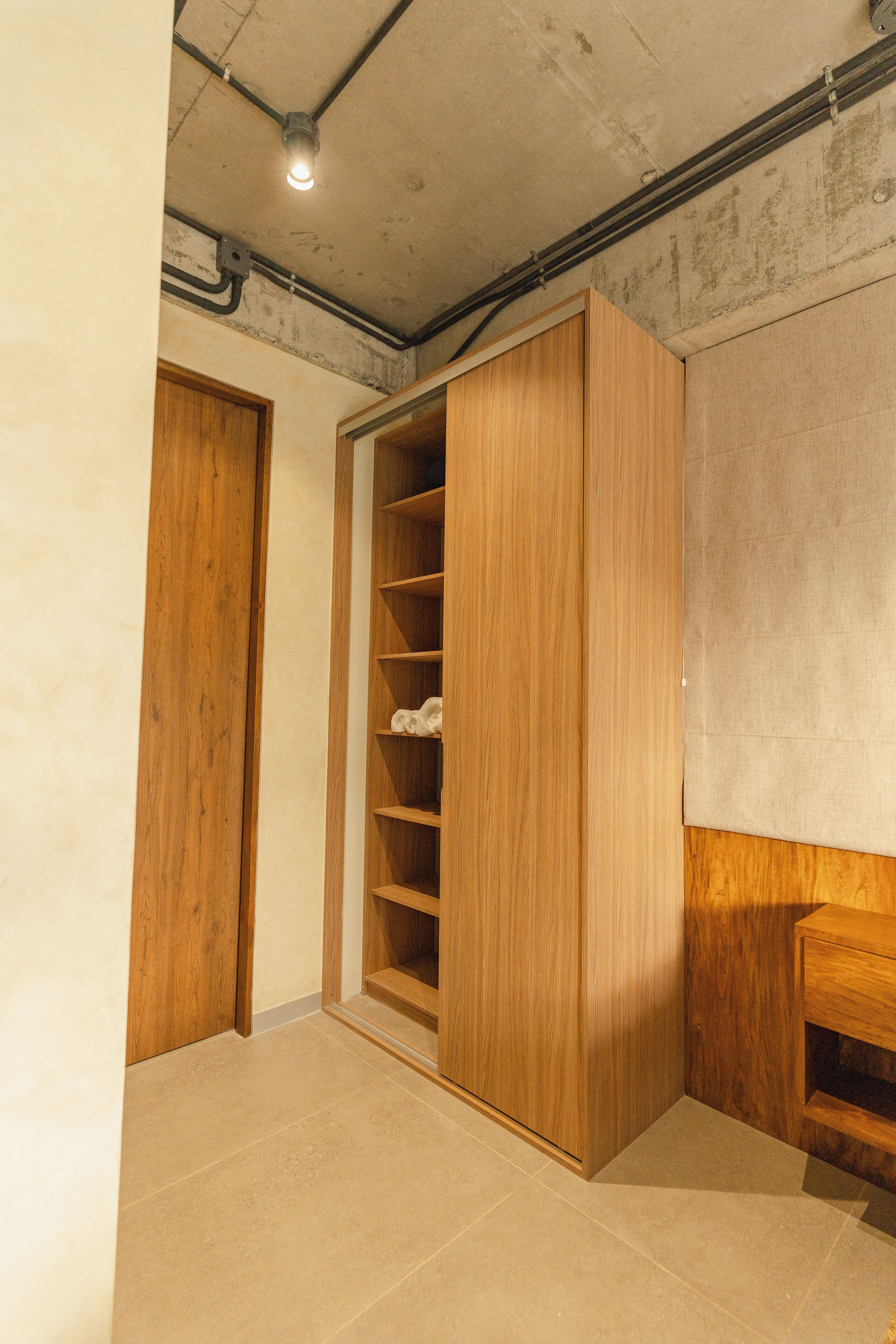 A room with a wooden wardrobe, a built-in shelf unit, and a tiled floor.