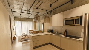 A modern kitchen with a microwave, refrigerator, and a dining area with a bench and table.