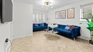 Ein modernes Wohnzimmer mit einem blauen Sofa, einem Glastisch und einer Deckenleuchte.