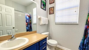 Un baño con lavamanos, tocador, inodoro y cortina de ducha.