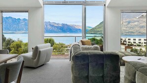 Una sala de estar moderna con un tragaluz grande, asientos cómodos y vistas a montañas y un lago.