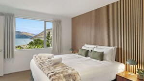 Un dormitorio moderno con una cama grande, vistas al exterior y un panel de pared de madera.