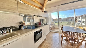 A modern kitchen with wooden beams, a large island, and a dining area with a view of the city. - CAP D'AGDE - Plage Richelieu / Réf 0156 (CAP D'AGDE)