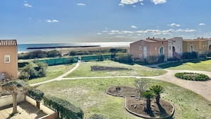 A coastal residential area with a clear view of the sea, a paved walkway, and a well-maintained lawn with a circular garden. - CAP D'AGDE - Plage Richelieu / Réf 0156 (CAP D'AGDE)