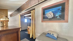A cozy room with a wooden desk, a lamp, a bunk bed, a sofa with a cushion, and a framed picture on the wall. - CAP D'AGDE - Plage Richelieu / Réf 0156 (CAP D'AGDE)
