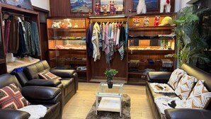 A cozy living room with leather sofas, a glass coffee table, and a wardrobe with hanging clothes. - Camino real (Puno)