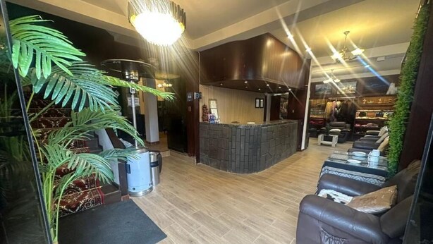 A modern lobby with a stone fireplace, leather seating, and a reception desk. - Camino real (Puno)