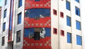 A multi-story building with a red and white facade, multiple windows, and a ground-level entrance. - Camino real (Puno)