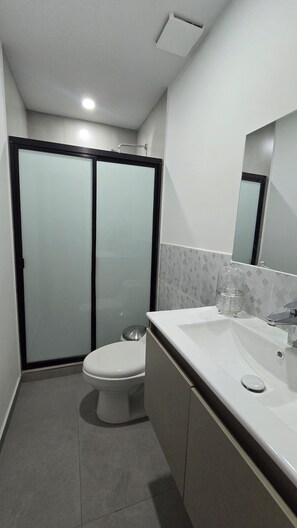 Ein modernes Badezimmer mit Toilette, Waschbecken und beschlagenen Glasduschtüren.