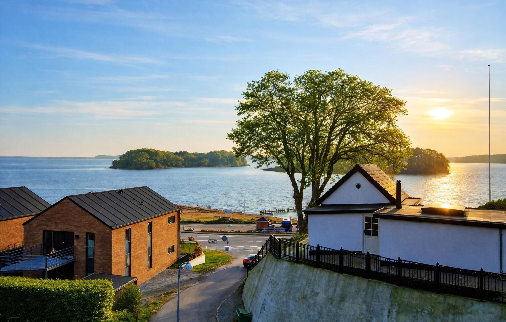 A coastal building with a view of the sea and a tree in front.